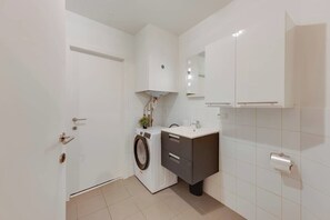 Ein kleines Badezimmer mit Waschmaschine, Waschbecken und Toilette.