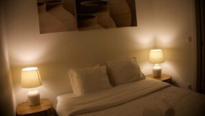 Una camera d'albergo con un letto, due lampade ai comodini e un'opera d'arte appesa al muro.