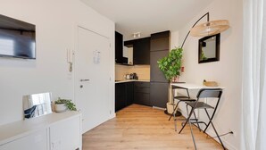 Una cucina compatta con elettrodomestici moderni, una zona pranzo con una sedia e una pianta in vaso.