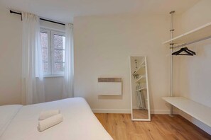 A bedroom with a bed, a window with curtains, a mirror, a radiator, and a wardrobe. - Stylish City Apartment with Lift in Antwerp Zuid (Antwerp)
