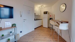 Een moderne keuken met een magnetron, koelkast en een houten aanrecht.