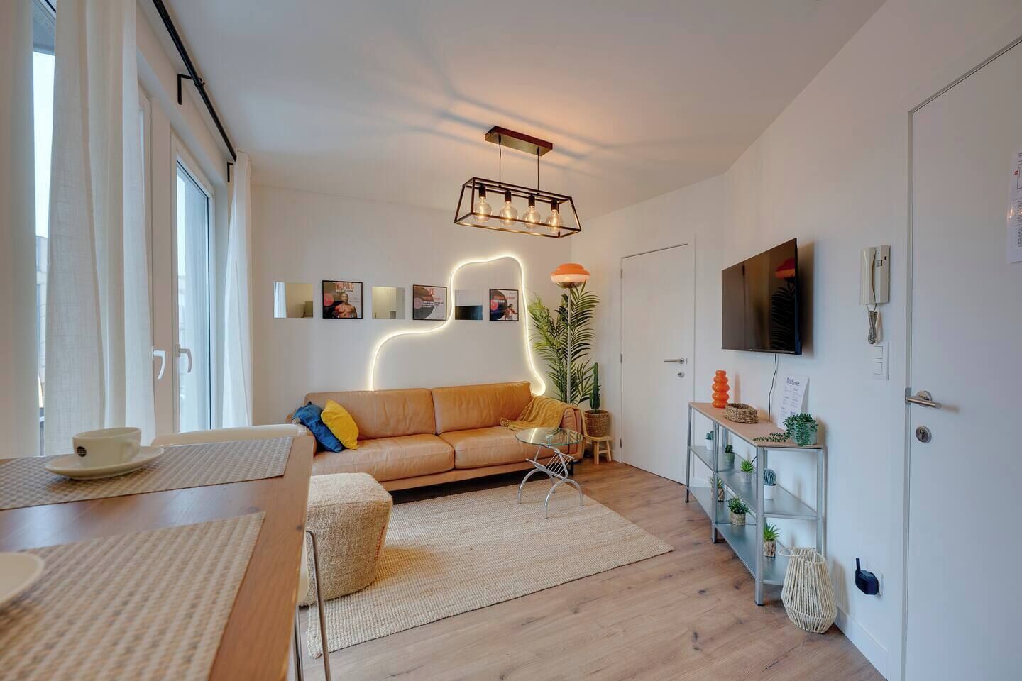 A modern living room with a sofa, a coffee table, a TV, and a plant.