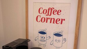 Een lijst met een bord waarop stripfiguren en de tekst 'Coffee Corner' staan, op een houten tafel.