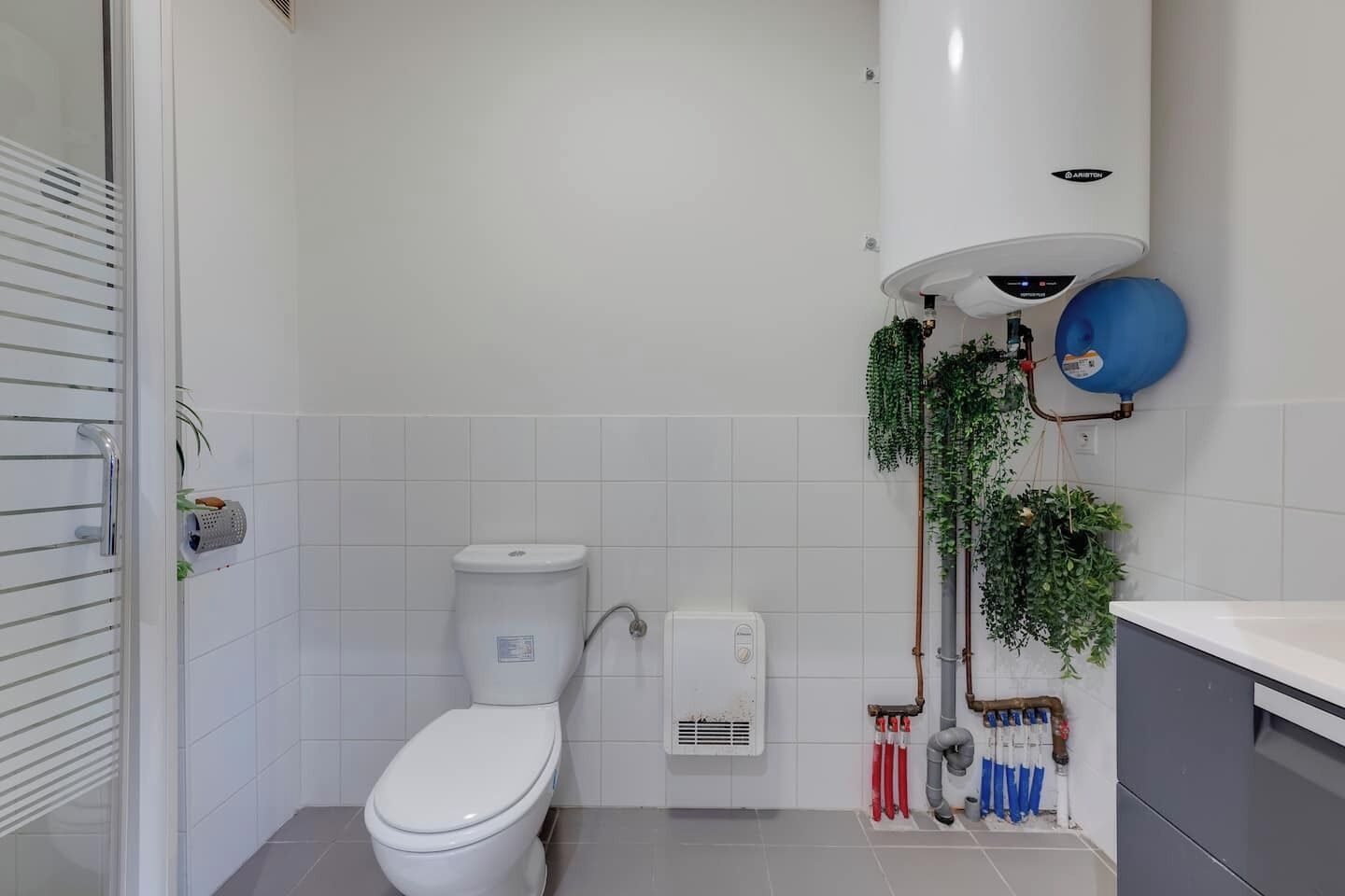 Une salle de bain moderne équipée de toilettes, d’un chauffe-eau et d’un espace douche.