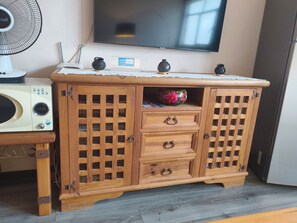 A wooden cabinet with drawers and a shelf, a microwave, and a television on the wall. - Oaxaca Loft (Oaxaca de Juárez)