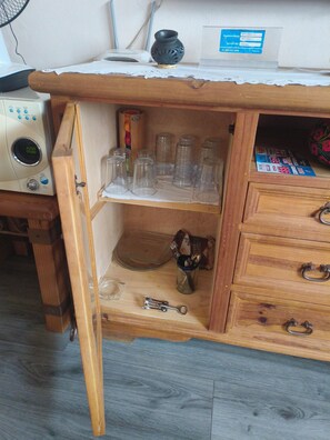 A wooden cabinet with multiple shelves, some containing glass jars and a metal bottle opener. - Oaxaca Loft (Oaxaca de Juárez)