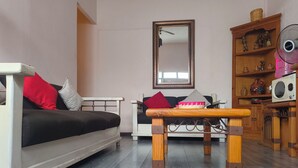 A living room with a sofa, a wooden table, a mirror, and a cabinet with decorative items. - Oaxaca Loft (Oaxaca de Juárez)