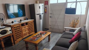 A living room with a TV, wooden furniture, a sofa, and a window with a view. - Oaxaca Loft (Oaxaca de Juárez)