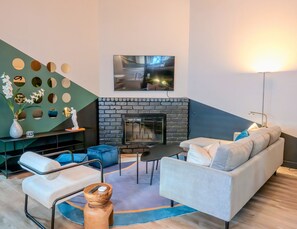 A modern living room with a fireplace, a sofa, a coffee table, and a TV mounted on the wall. - Spacious Las Vegas Retreat with Modern Comforts in a Convenient Location (Las Vegas)