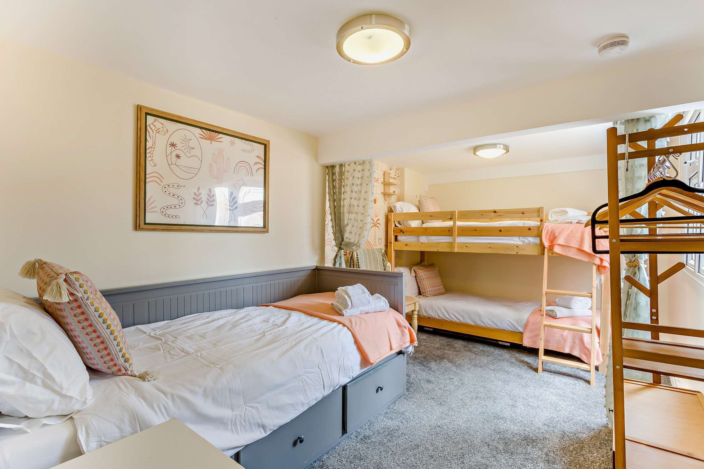 A bedroom with two bunk beds, a bedside table, a wardrobe, and a ceiling light.