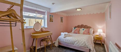 Una camera da letto con un letto, una cassettiera in legno, una sedia, uno specchio e una finestra con vista sull'esterno.