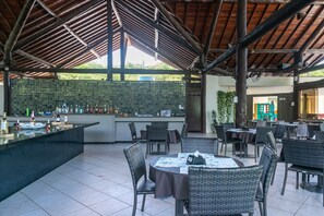 An outdoor dining area with a bar, wicker furniture, and a tiled floor. - Nannai Residence Muro Alto Beira Mar (Ipojuca)