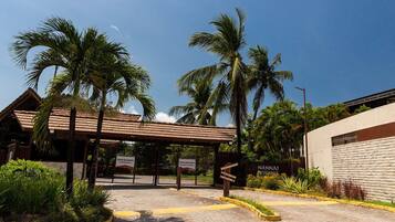 A gated entrance with palm trees, a covered walkway, and a building labeled 'NAUNAI RESIDENCE'.