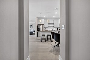 Una cocina moderna con una isla central, luces colgantes y una zona de comedor con taburetes de bar.