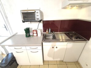 A compact kitchenette with a microwave, sink, and cabinets.