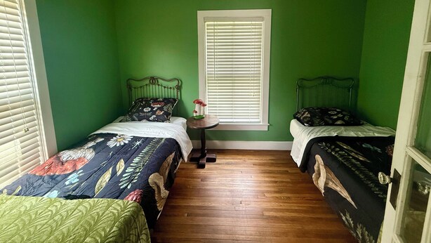 A room with two single beds, a small table, and a window with blinds. - Cozy 2-bedroom cottage on with AC in charming Alderson (Alderson)