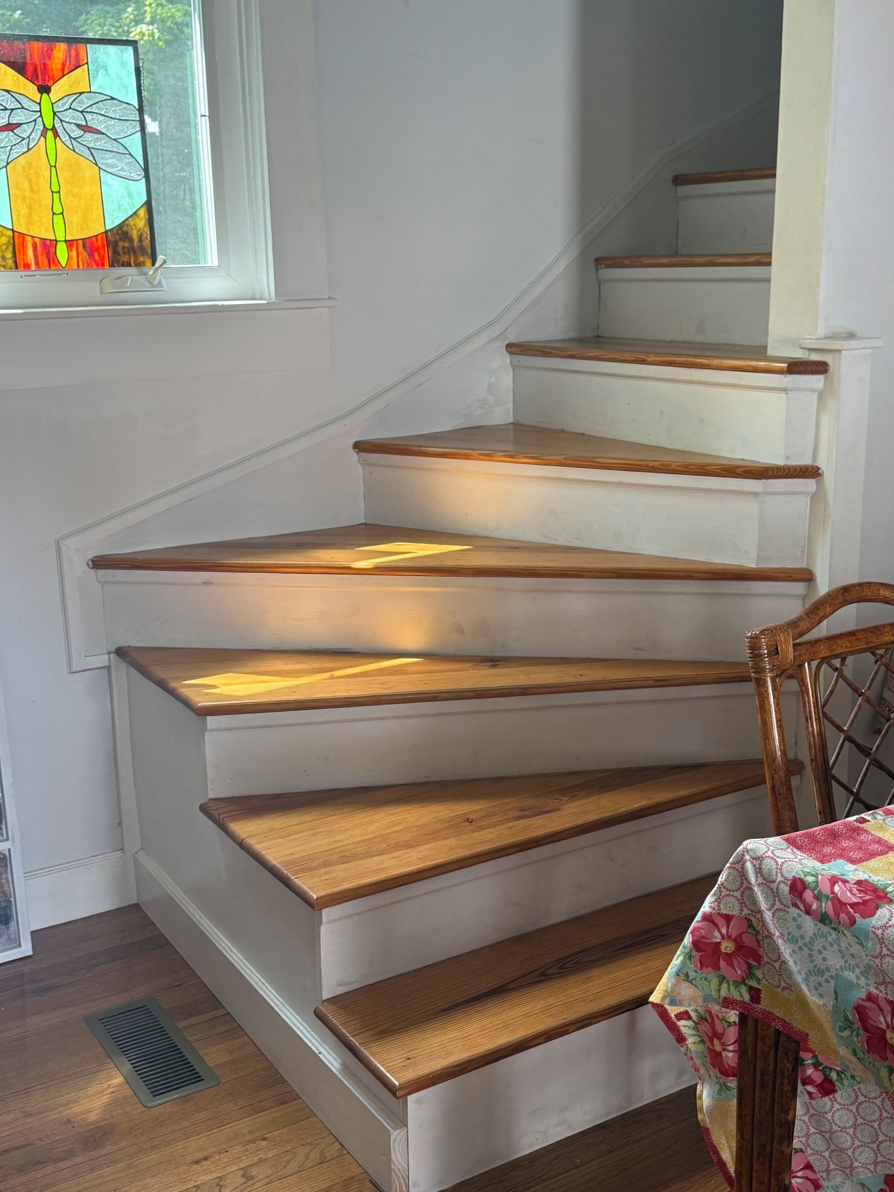 A staircase with wooden steps and a stained glass window.