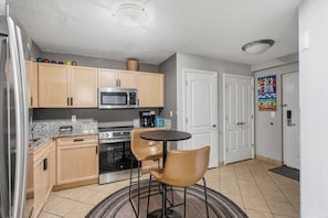 A compact kitchen with a microwave, stove, and a small dining area with two chairs.