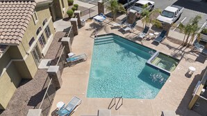 A rooftop pool with clear water, surrounded by lounge chairs and a few vehicles in the background. - Desert Luxe / Pool • Balcony • Workspace (Phoenix)