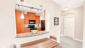 Eine moderne Küche mit Holzschränken, einer Granit Arbeitsplatte und einem Essbereich mit einem Holztisch und Metallstühlen.