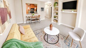 Ein Wohnzimmer mit einer Couch, einem Couchtisch, einem Fernseher und einem Deckenventilator.