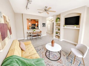 A living room with a sofa, a coffee table, a TV, and a ceiling fan.