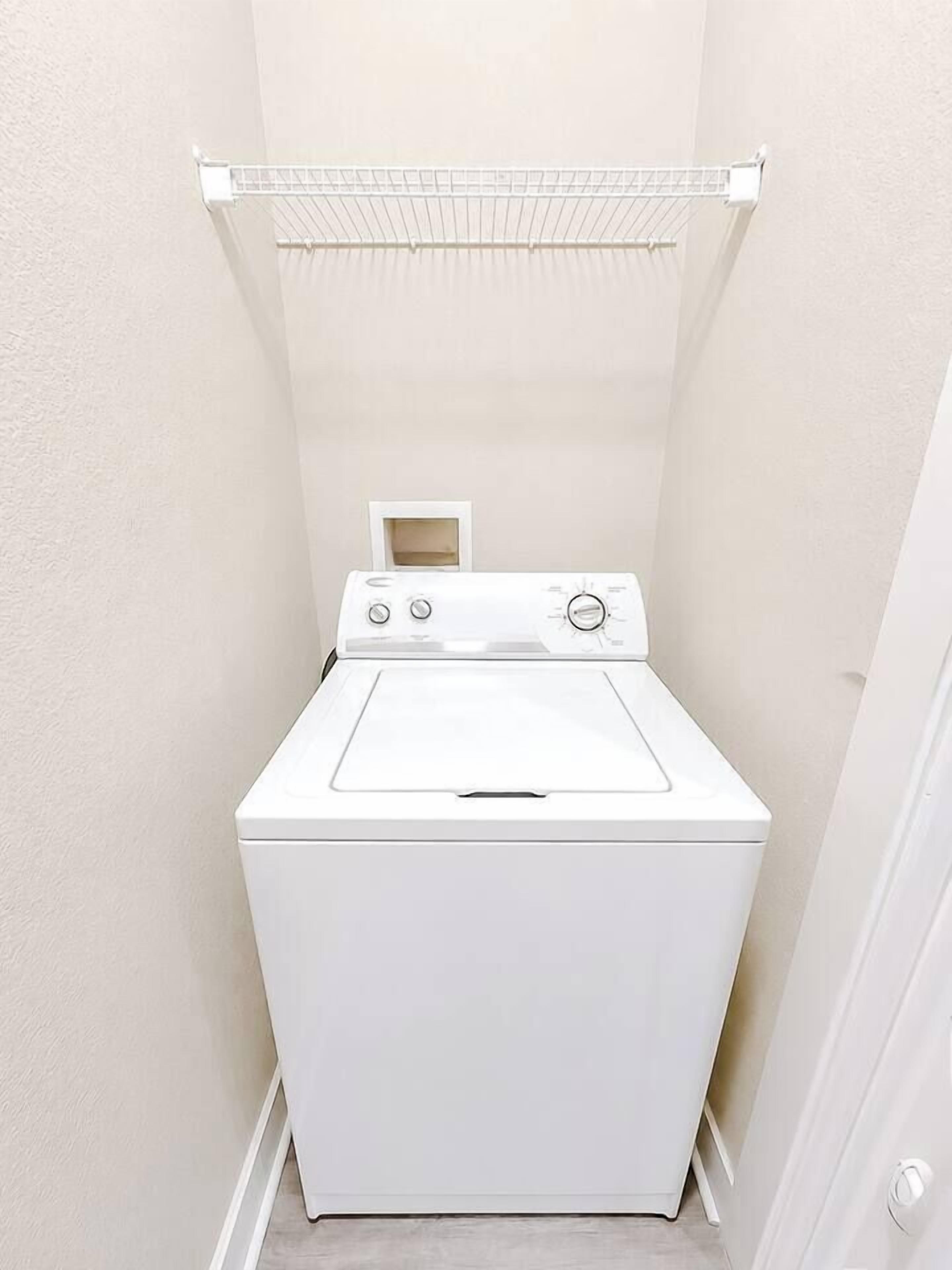 Ein kleiner Hauswirtschaftsraum mit einer weißen Waschmaschine und einem Wäscheständer.