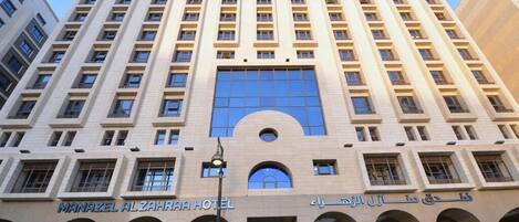 Un hotel de varios pisos con una entrada central en arco y múltiples balcones.
