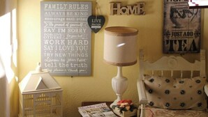 A cozy room with a bed, a lamp, a chair, and various wall decorations including clocks and motivational signs. - Shabby chic cottage with pool in Chianti (Castellina in Chianti)