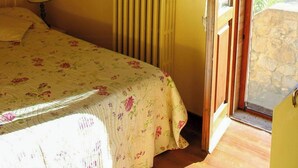 A bedroom with a bed, a radiator, a ceiling fan, a painting, and a door leading to an outdoor area. - Shabby chic cottage with pool in Chianti (Castellina in Chianti)