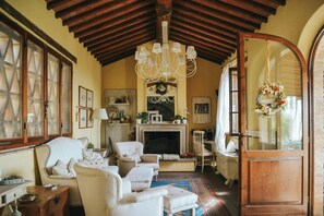 A cozy living room with a fireplace, comfortable seating, and a chandelier. - Shabby chic cottage with pool in Chianti (Castellina in Chianti)