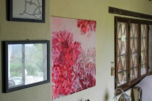 A room with a large floral artwork, a framed abstract painting, and a window with a view of greenery. - Shabby chic cottage with pool in Chianti (Castellina in Chianti)