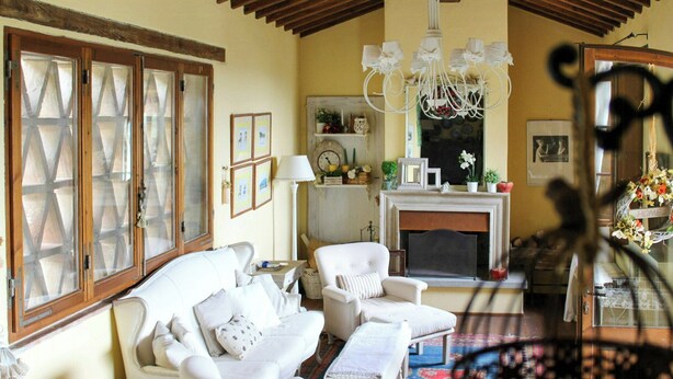 A cozy living room with a fireplace, white furniture, and a chandelier. - Shabby chic cottage with pool in Chianti (Castellina in Chianti)