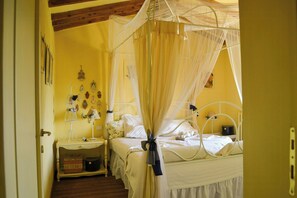 A bedroom with a canopy bed, bedside tables, and decorative wall hangings. - Shabby chic cottage with pool in Chianti (Castellina in Chianti)