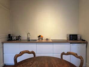 Eine kleine Küche mit Spüle, Toaster, Mikrowelle und einer Obstschale auf der Arbeitsfläche.