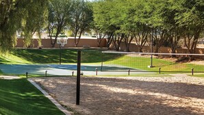 A basketball court with a net, surrounded by sand, trees, and a fence. - Coachella2ndWeek: Cozy 1-bedroom, 2 bed condo in Palm Desert
 AC & resort access (Palm Desert)