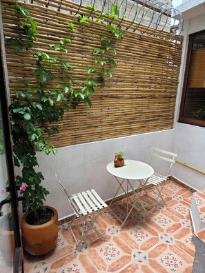 A small outdoor seating area with a table and chairs, a potted plant, and a bamboo screen. - A great location with contemporary comfort and the richness of Oaxacan culture. (Oaxaca de Juárez)
