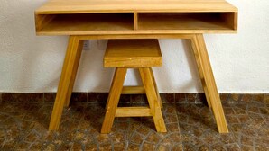 A wooden desk with a shelf, positioned against a white wall with a framed artwork and two decorative items. - A great location with contemporary comfort and the richness of Oaxacan culture. (Oaxaca de Juárez)