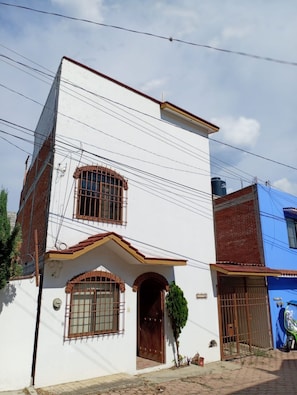 A two-story building with a white facade, a brown door, and barred windows. - A great location with contemporary comfort and the richness of Oaxacan culture. (Oaxaca de Juárez)