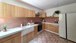 A modern kitchen with wooden cabinets, a stainless steel sink, and a white refrigerator. - A great location with contemporary comfort and the richness of Oaxacan culture. (Oaxaca de Juárez)