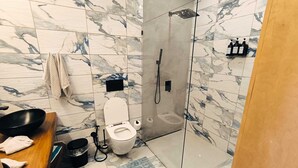 A bathroom with a toilet, a shower, a sink, and a towel rack. - Surf One (Sosúa)