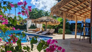 A swimming pool with lounge chairs and a thatched roof structure. - Surf One (Sosúa)