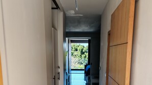 A hallway with a wooden wardrobe, a marble floor, and a view of a balcony with a blue sky. - Surf One (Sosúa)