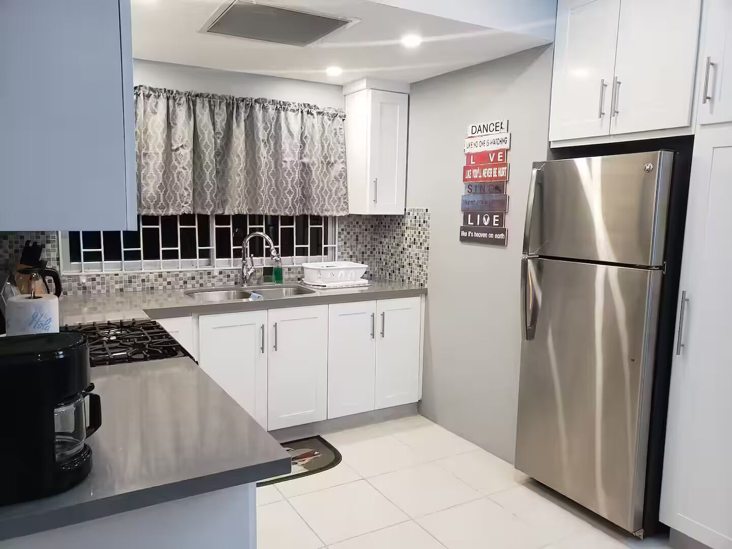 A modern kitchen with white cabinets, a stainless steel refrigerator, and a tiled backsplash.