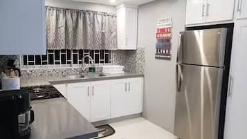 A modern kitchen with white cabinets, a stainless steel refrigerator, and a tiled backsplash.