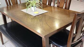 A dining table with six wooden chairs, a potted plant, and a placemat.
