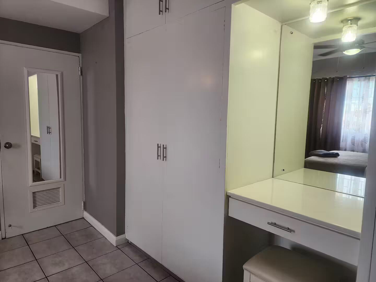 Ein Zimmer mit Schrank, Spiegel und Sitzbank.