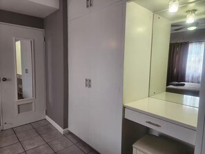 Una habitación con armario, espejo y banco.