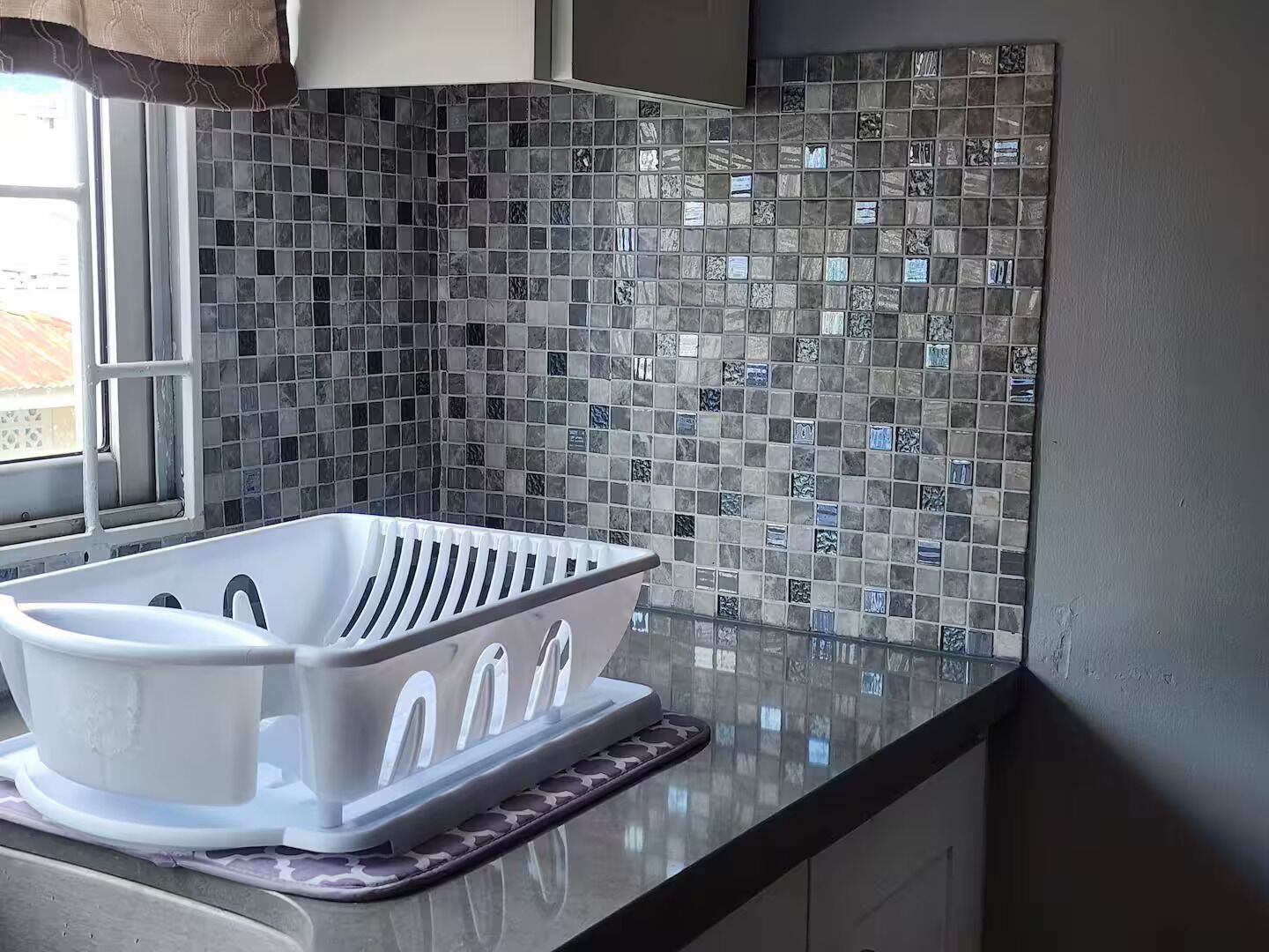 Una cocina con un lavabo blanco, una ventana y salpicadero de azulejos.