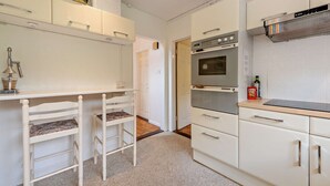 A compact kitchen with white cabinetry, a built-in oven, and a coffee machine. - Host & Stay | Worthing Getaway (Worthing)